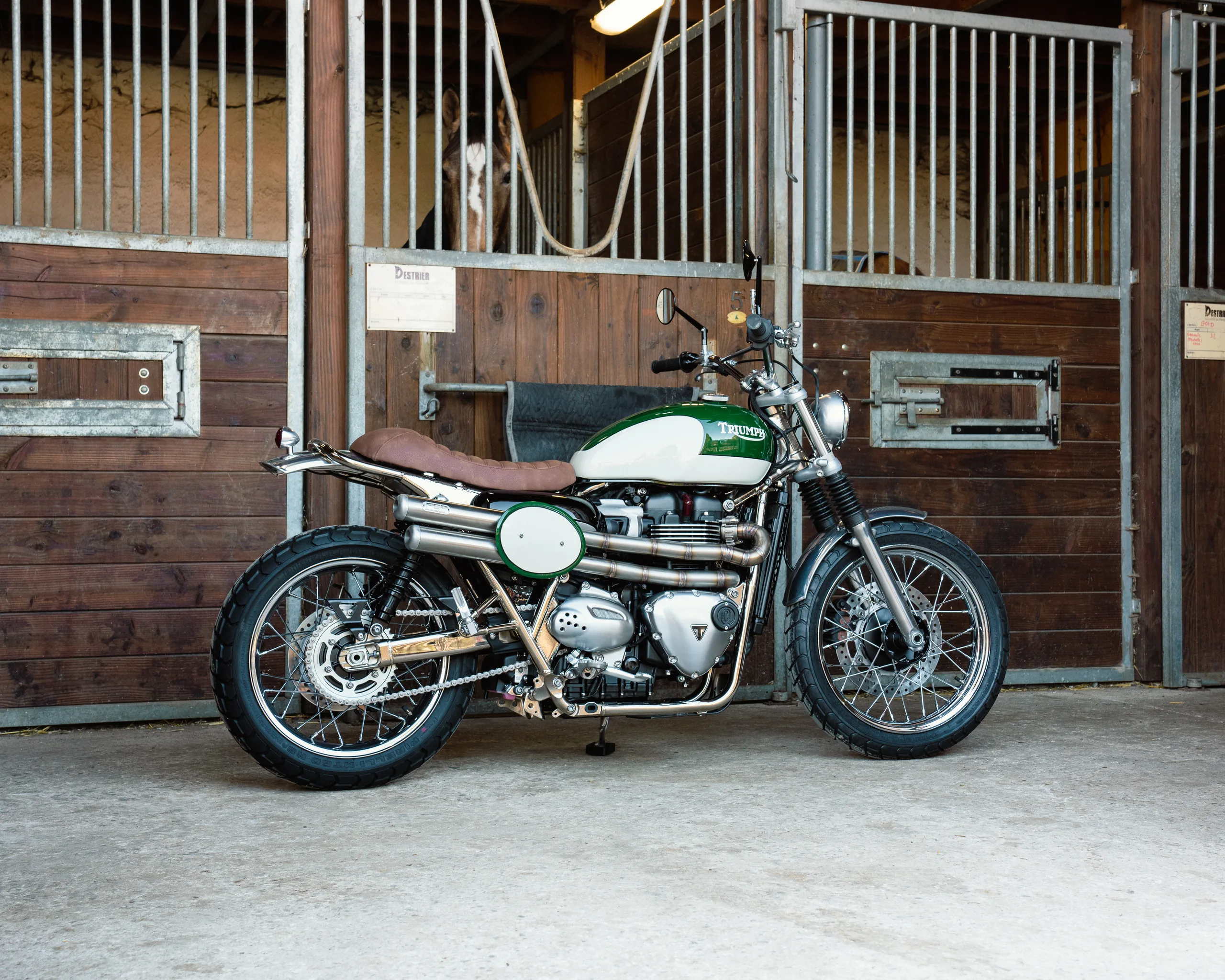 Triumph Legend FCR Original verte et blanche garée devant des boxes d'écurie en bois