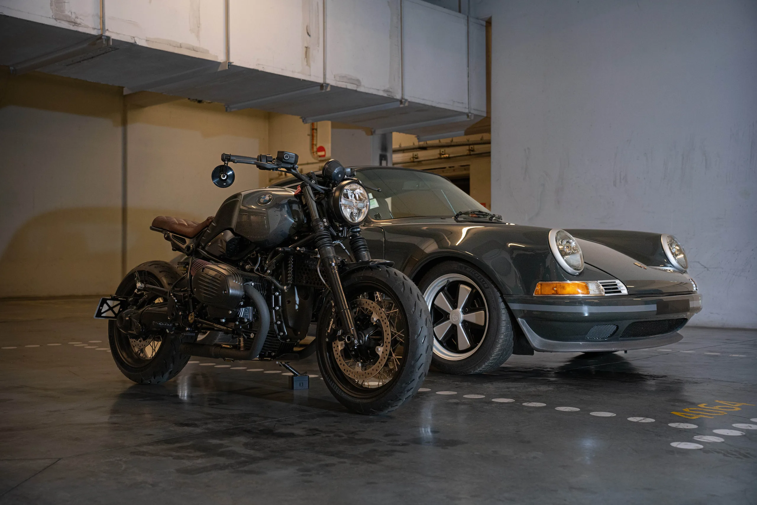 BMW R nineT Urban FCR Original noire garée à côté d'une Porsche 911 ancienne
