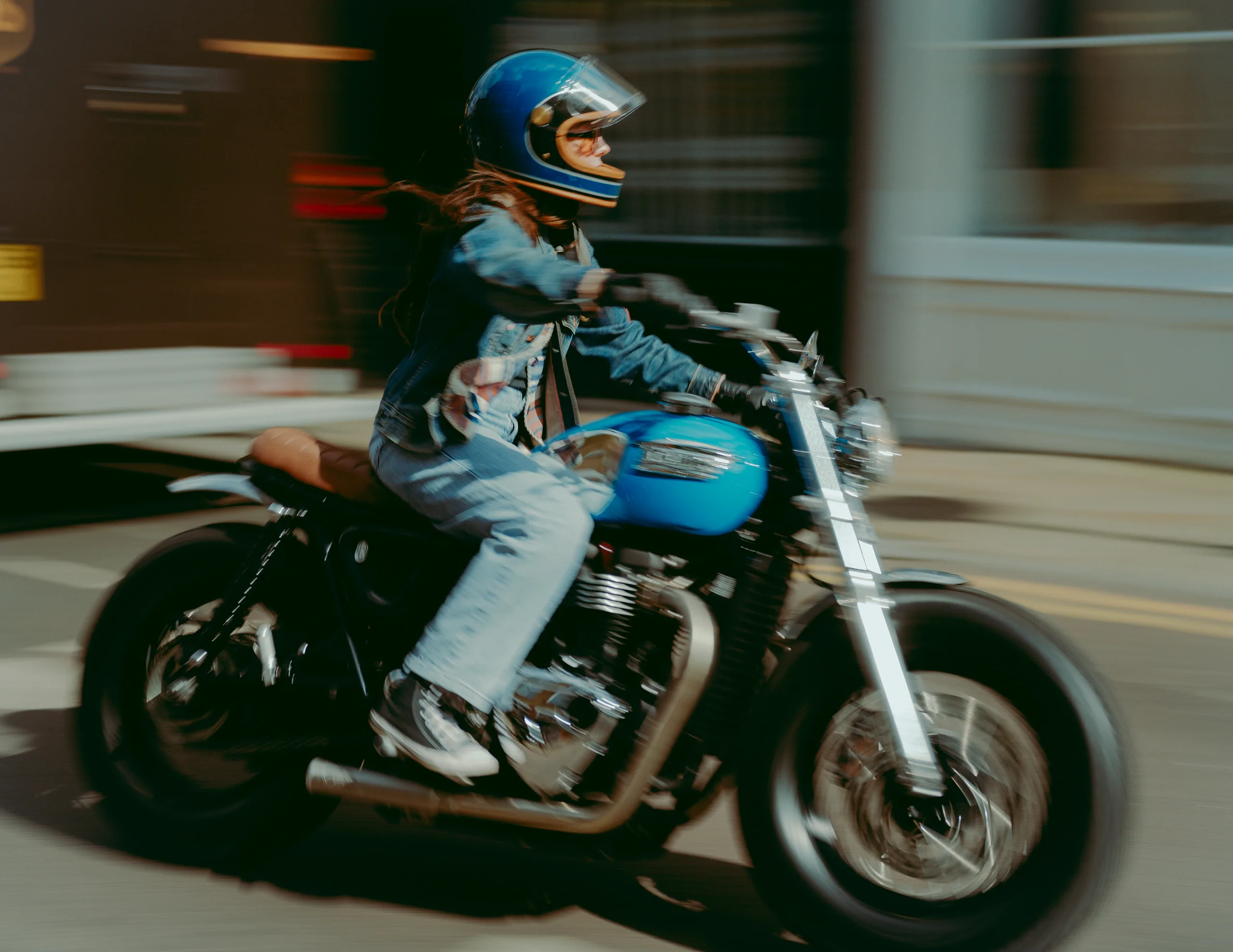 Pilote en jean et casque bleu roulant en Triumph Fat Bike FCR Original turquoise en ville