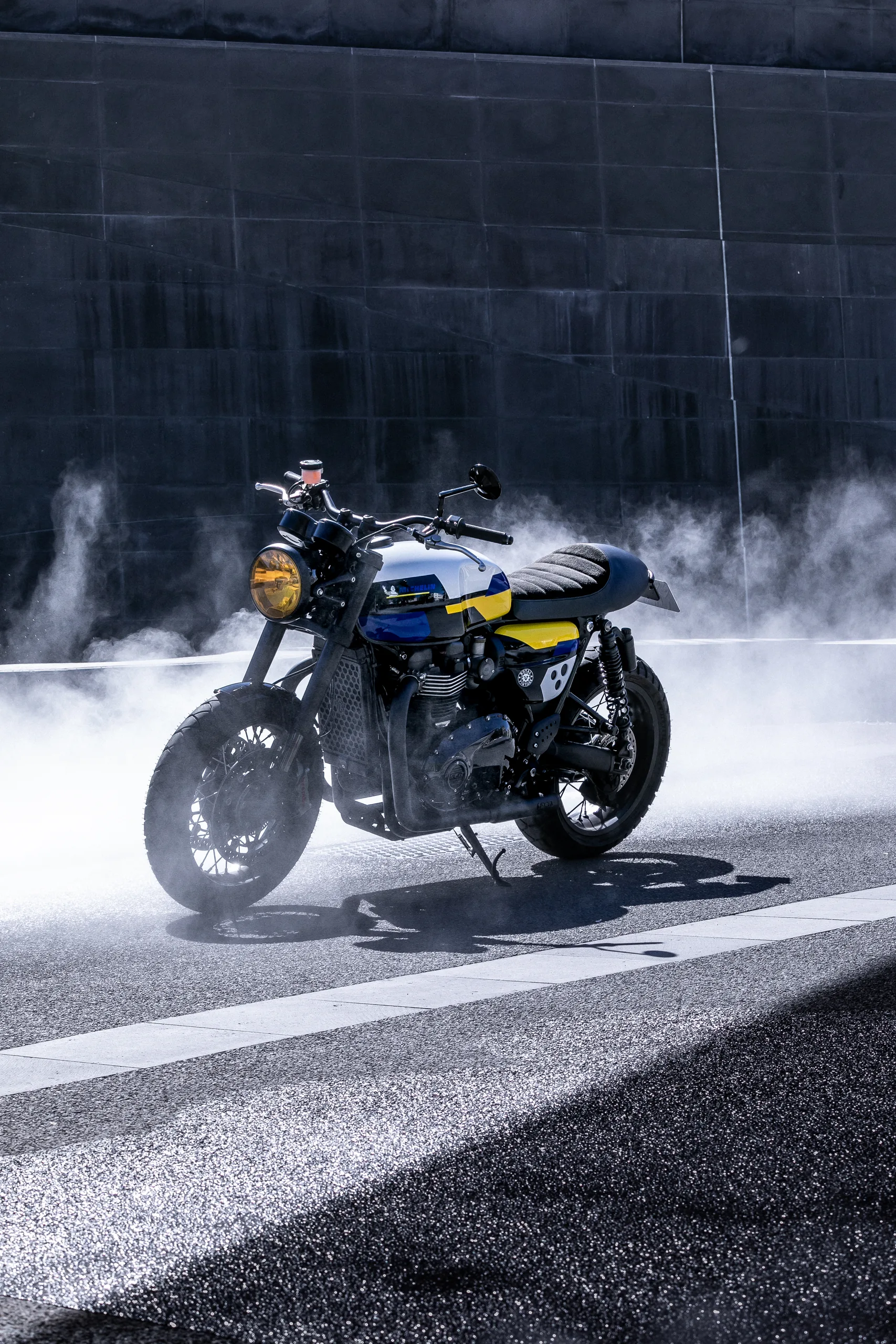 Triumph Thruxton Roadster Classic FCR Original bleue, jaune et blanche entourée de fumée