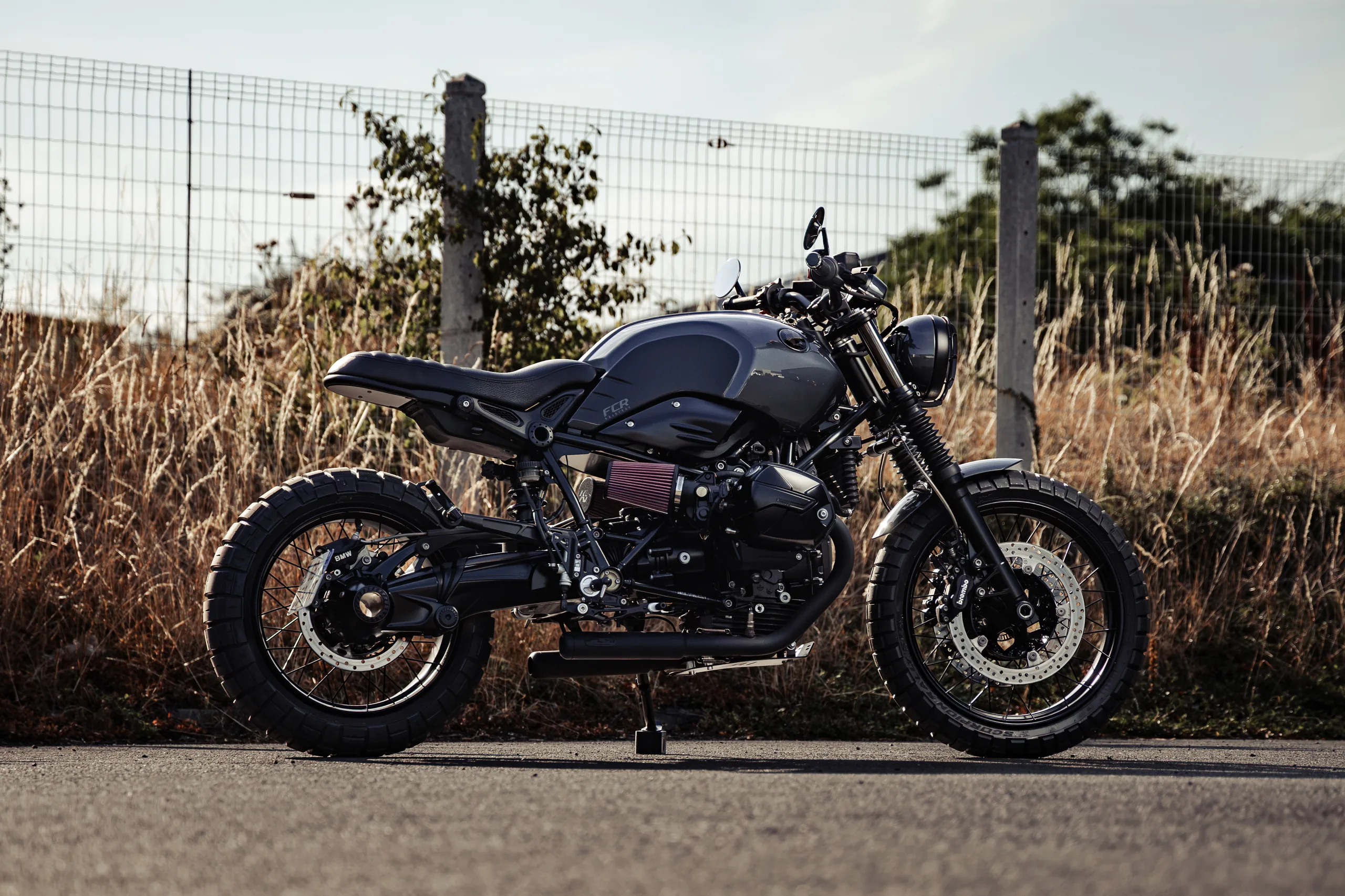 BMW R nineT Urban FCR Original gris anthracite garée devant un grillage et des herbes sèches