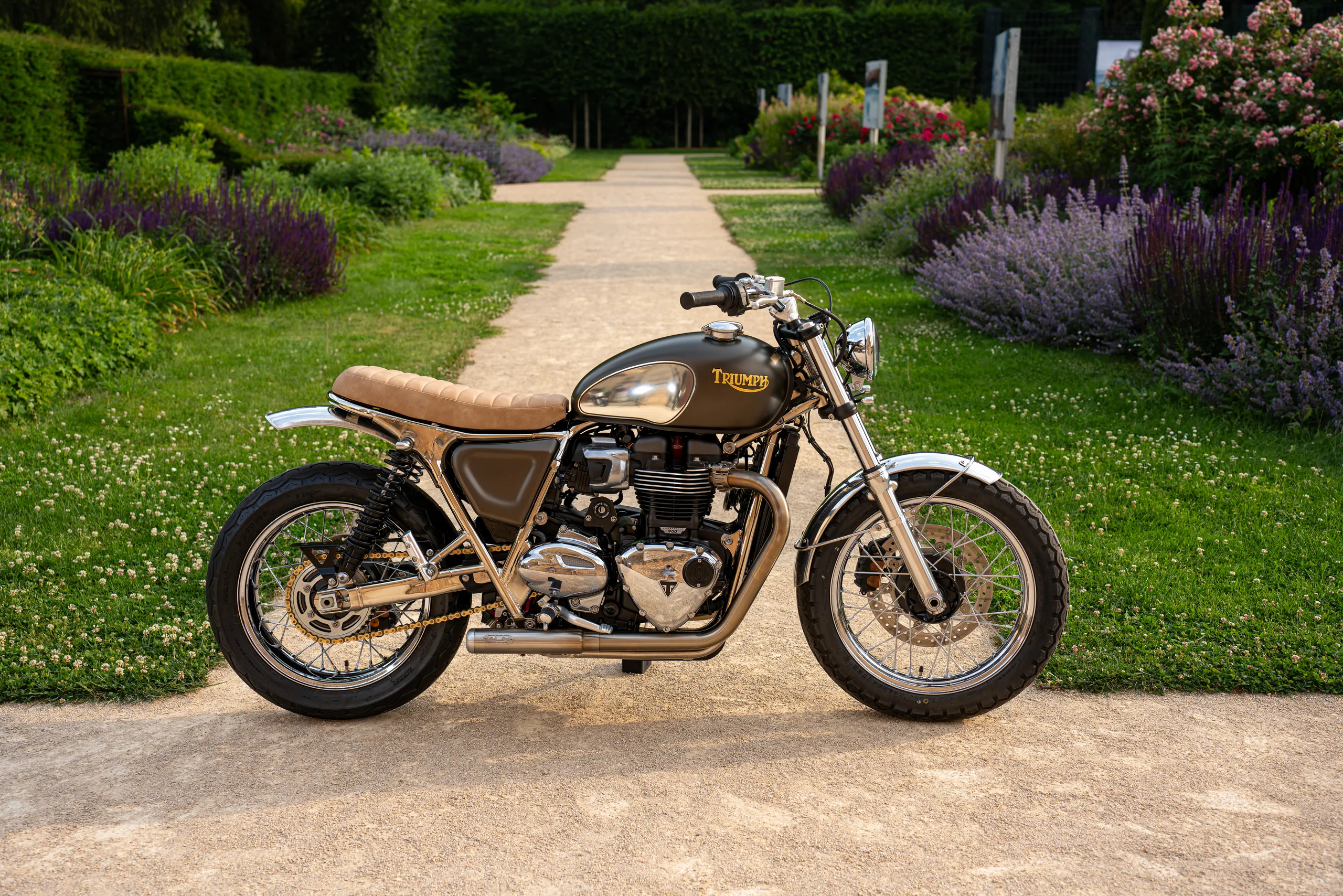 Vue de profil d'une Triumph Ride & Chrome FCR Original kaki sur une allée de jardin