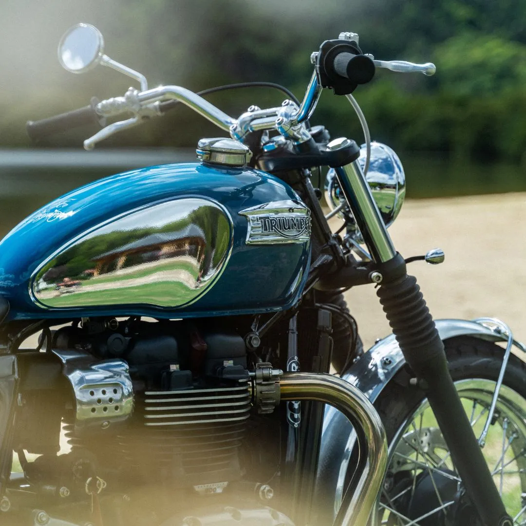 Triumph Speed Twin bleue vintage devant un lac. Parfaite pour les amateurs de motos rétro et de beaux paysages.