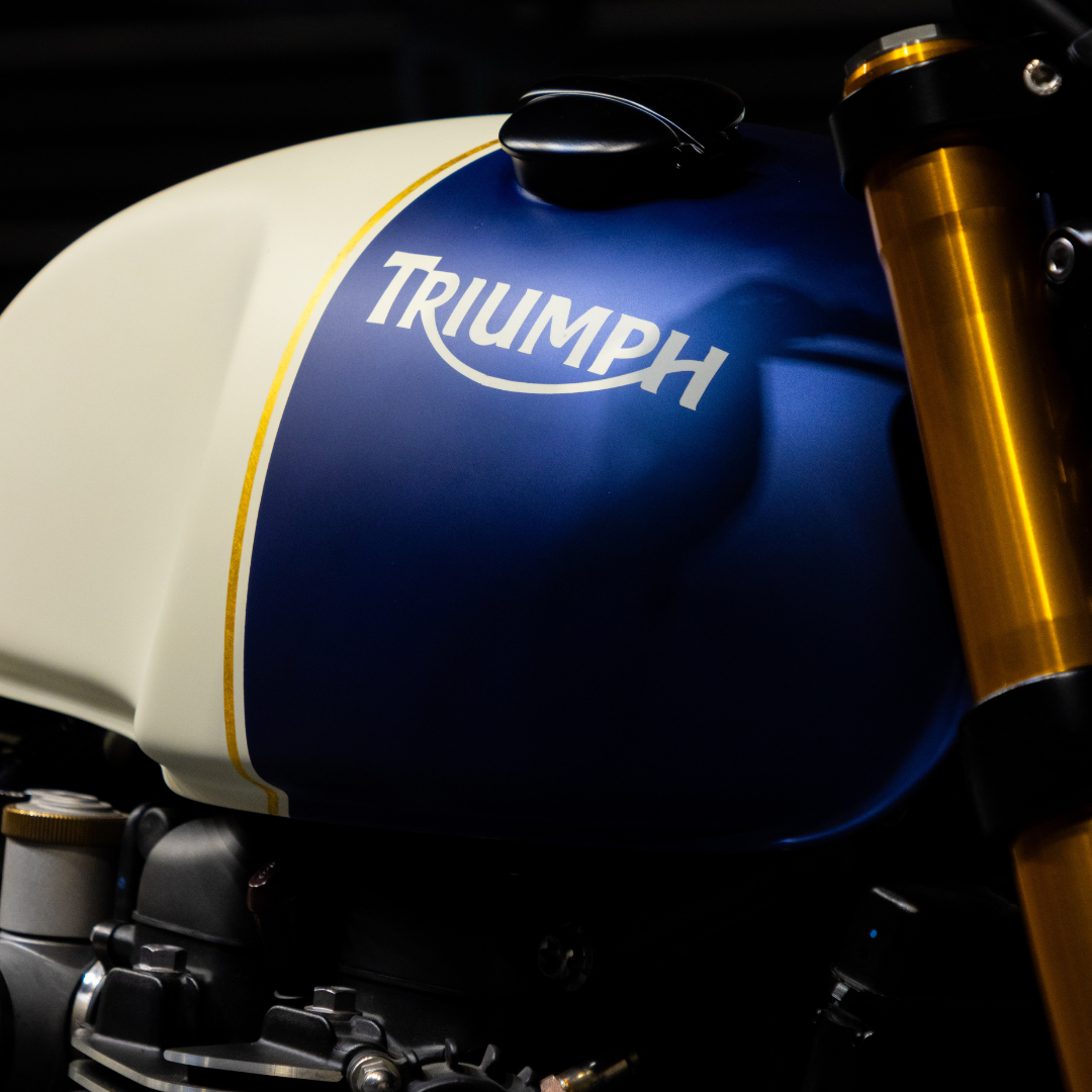 Triumph Thruxton RS avec une carrosserie bleue et des accents dorés, design élégant et sportif de profil