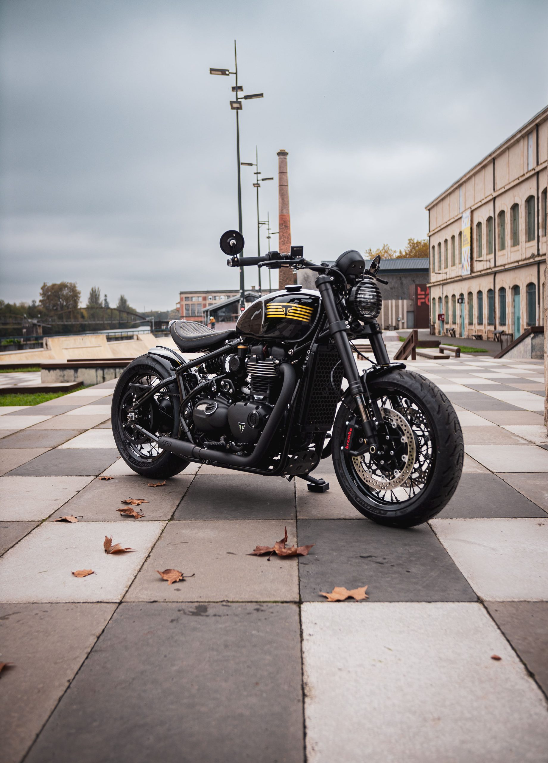 Triumph Bobber custom FCR Original devant un bâtiment industriel
