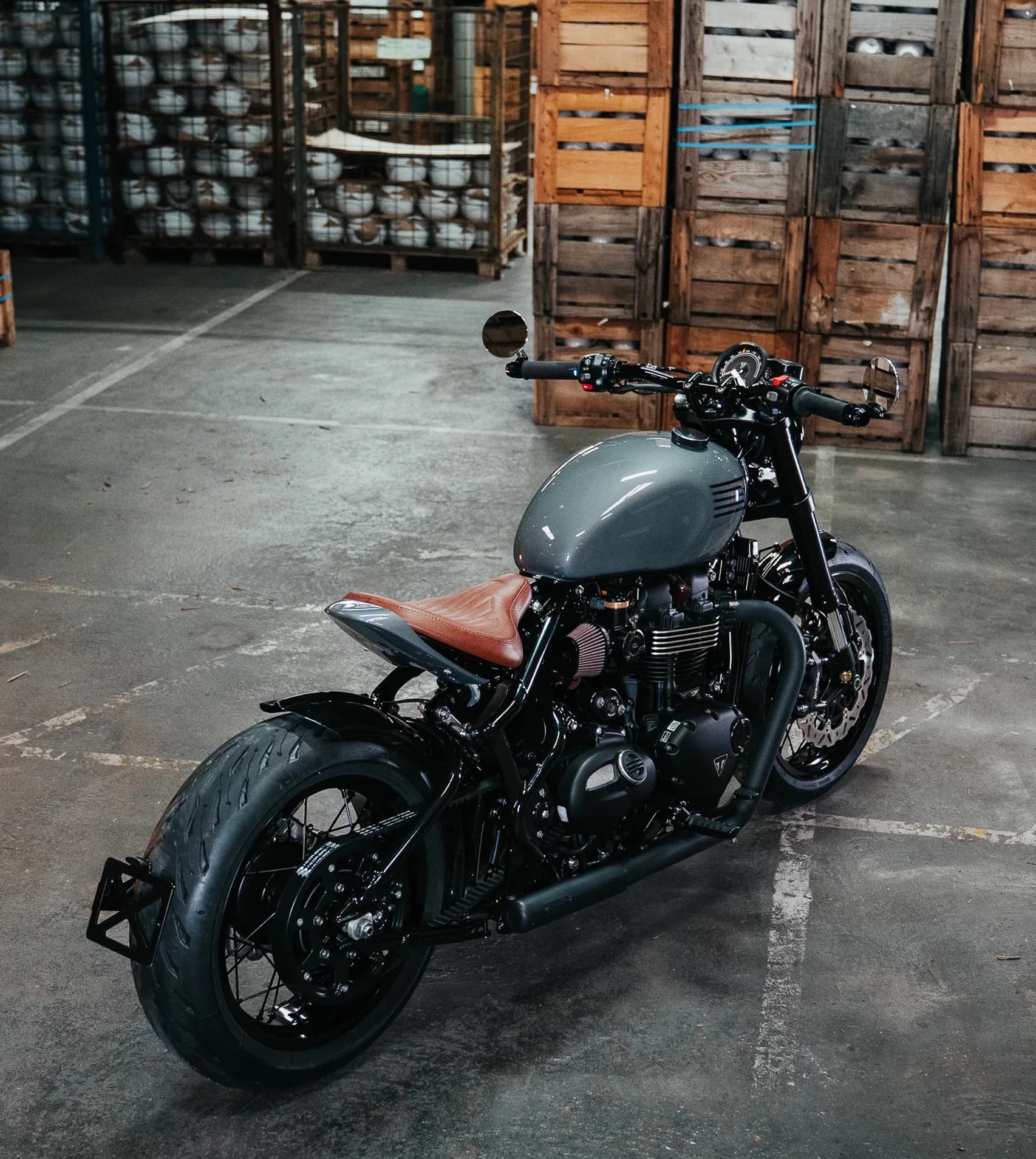 Triumph Bobber FCR Original avec selle en cuir marron et finitions soignées dans un entrepôt