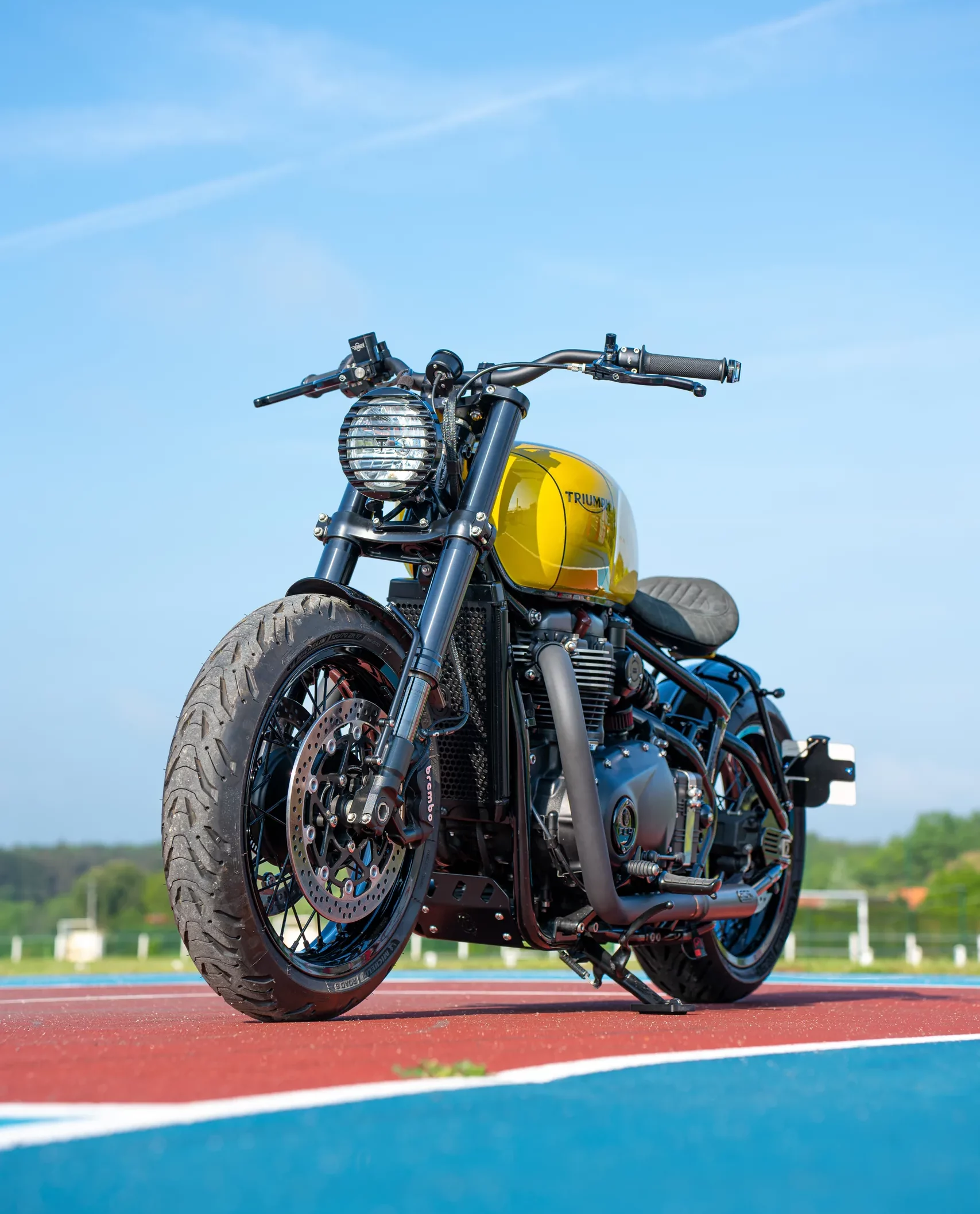 Triumph Bobber FCR Original réservoir jaune vue de face sous un ciel bleu